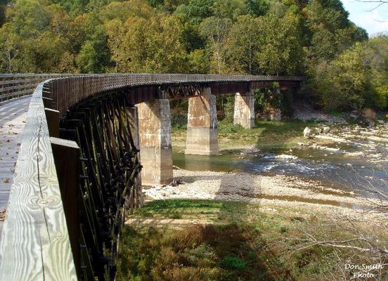 Alvarado - Railroad Trestle
A RAILROAD FROM ABINGDON, VA. LINKING SEVERAL SMALL TOWNS AND COMMUNITIES WAS STARTED IN THE 1880s.  BY 1918 IT RAN FROM ABINGDON TO ELKLAND, N. C. WHICH IS NOW CALLED TODD.  DAMASCUS, TAYLOR'S VALLEY, GREEN COVE AND WHITE TOP WERE AMONG THE STOPS ON IT'S ROUTE.  THERE WERE 100 TRESTLES AND BRIDGES ON THE RAIL LINE.
 
THE VIRGINIA CREEPER WAS STEAM POWERED AND HAULED FREIGHT AND PASSENGERS.  THE STEAM ENGINE WAS REPLACED BY N&W IN 1956 WITH A DIESEL LOCOMOTIVE.   IT CONTINUED IN OPERATION UNTIL MARCH 31, 1977 WHEN THE LAST TRAIN RAN.  THE ROADBED HAS BEEN CONVERTED TO A VERY POPULAR HIKING-BIKING TRAIL.  PICTURED IS THE TRESTLE AT THE HEADWATERS OF SOUTH HOLSTON LAKE WHERE THE MIDDLE AND SOUTH FORKS OFTHE HOLSTON RIVER MEET.  Courtesy of Don Smith [email]dsmith1043@comcast.net[/email]
 

